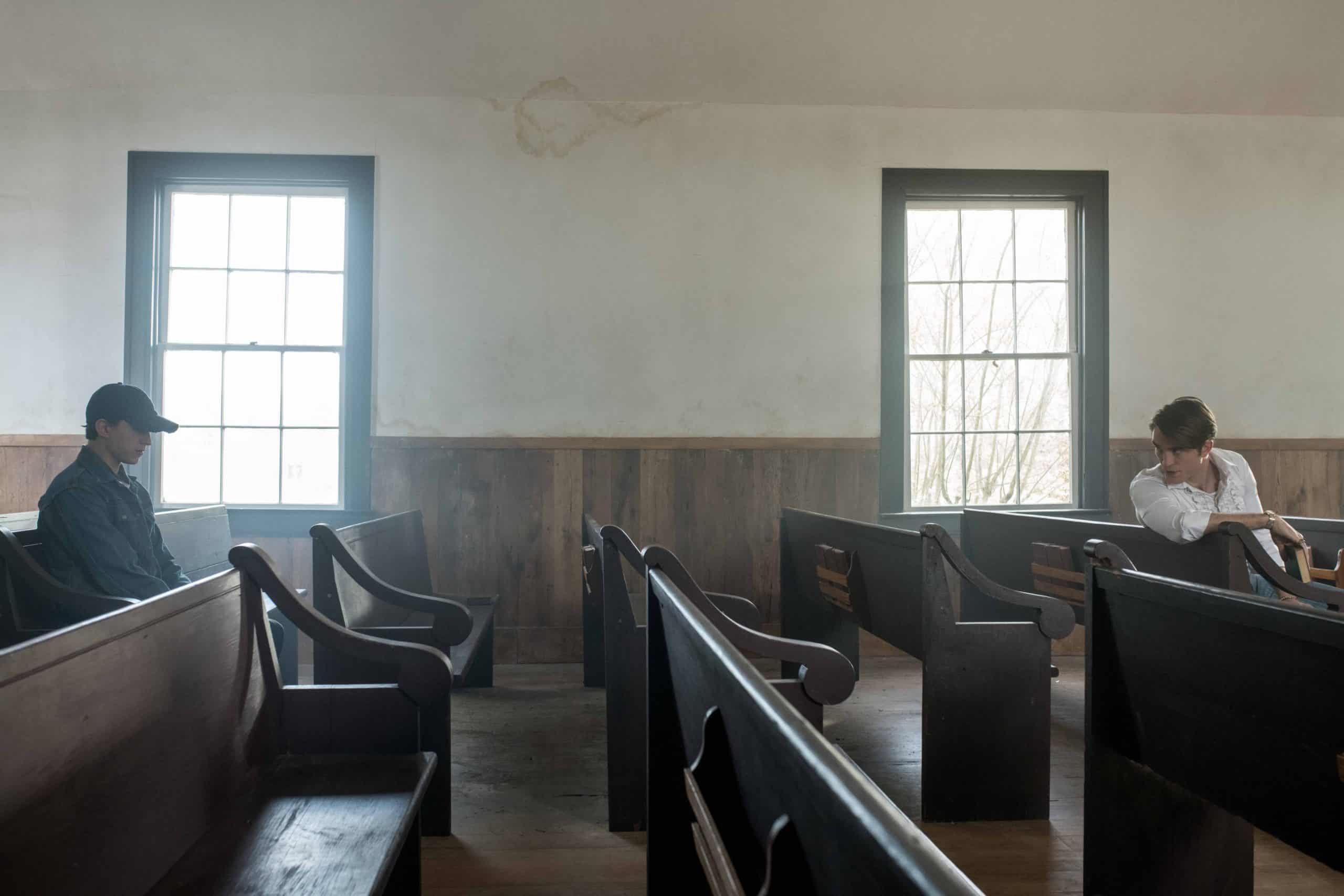 Robert Pattinson e Tom Holland sentados em banco de igreja